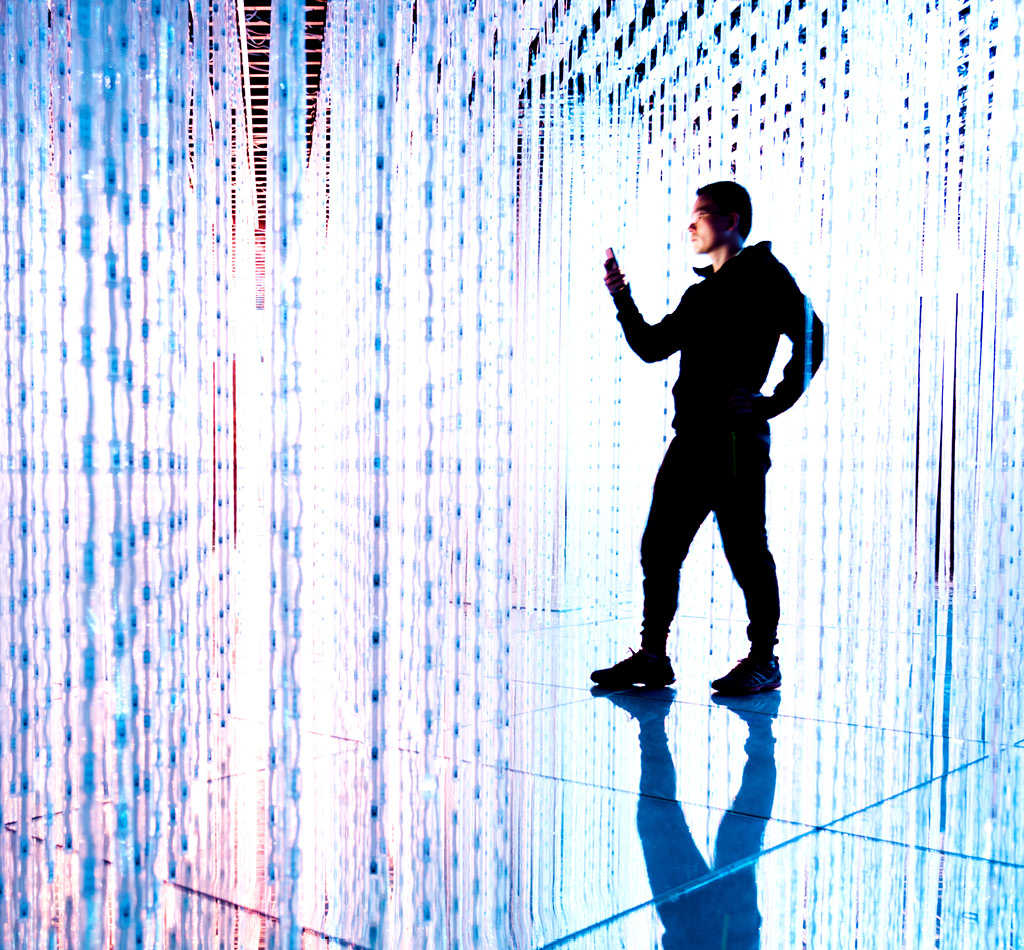 Person using phone in a bright room full of colourful lights.