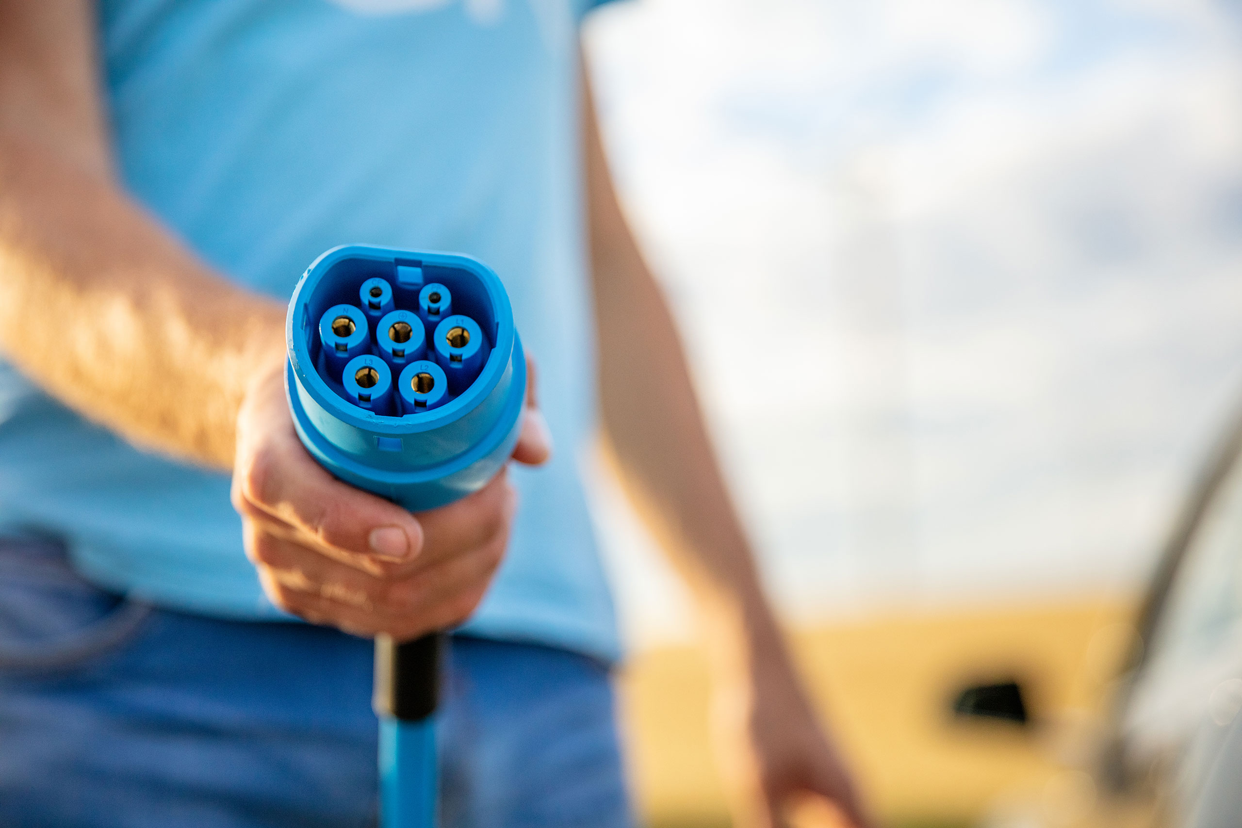 http://image%20of%20a%20man%20standing%20by%20car%20and%20holding%20electric%20charger